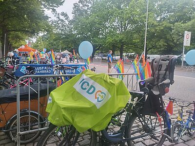 Fahrrad mit VCD-Fahne über dem Lenker und vorderen Gespäckträger, sowie Kindersitz hinter dem Sattel und kleinem Kinderfahrrad hinten dran steht in einer Allee