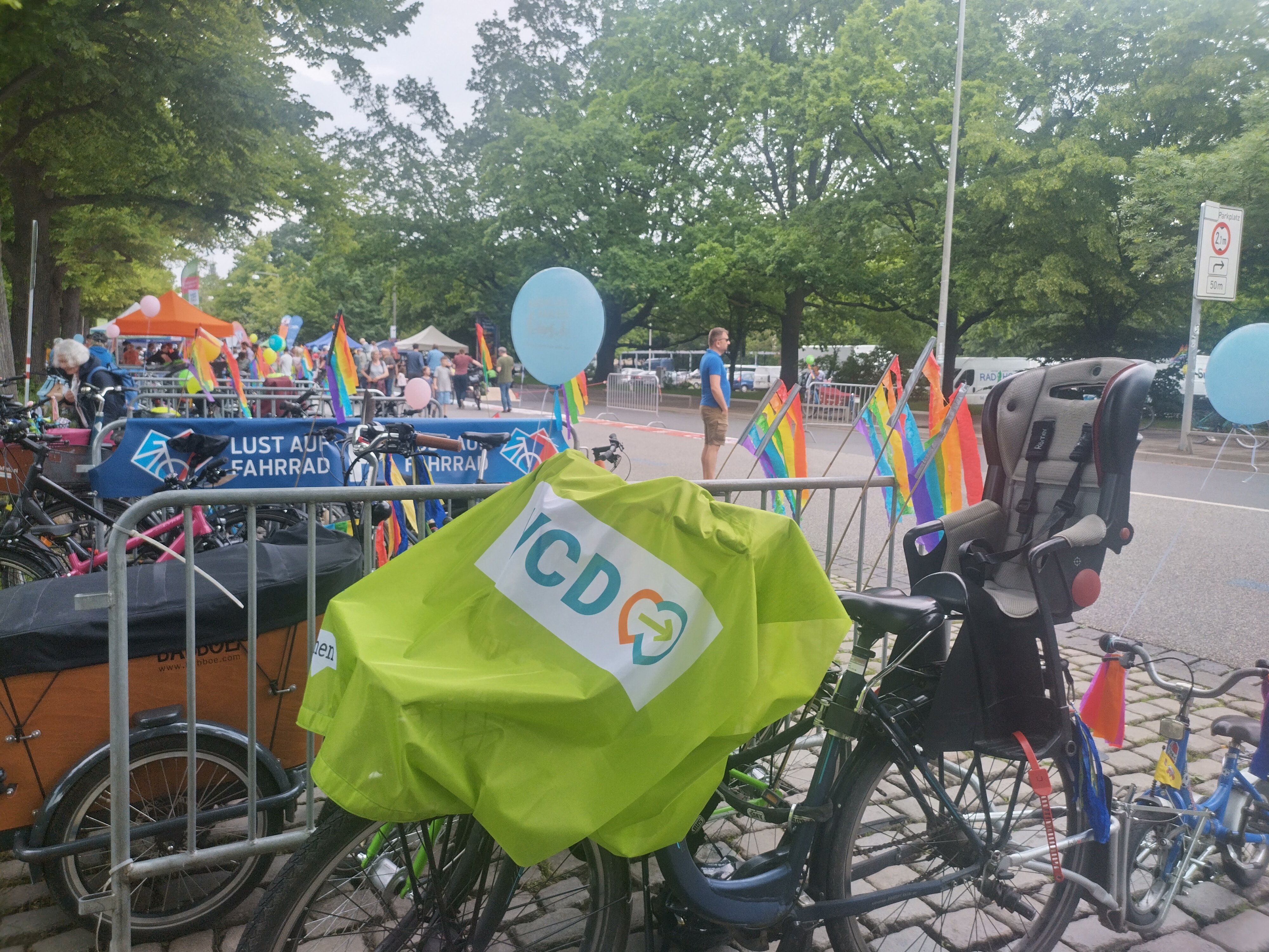 Fahrrad mit VCD-Fahne über dem Lenker und vorderen Gespäckträger, sowie Kindersitz hinter dem Sattel und kleinem Kinderfahrrad hinten dran steht in einer Allee